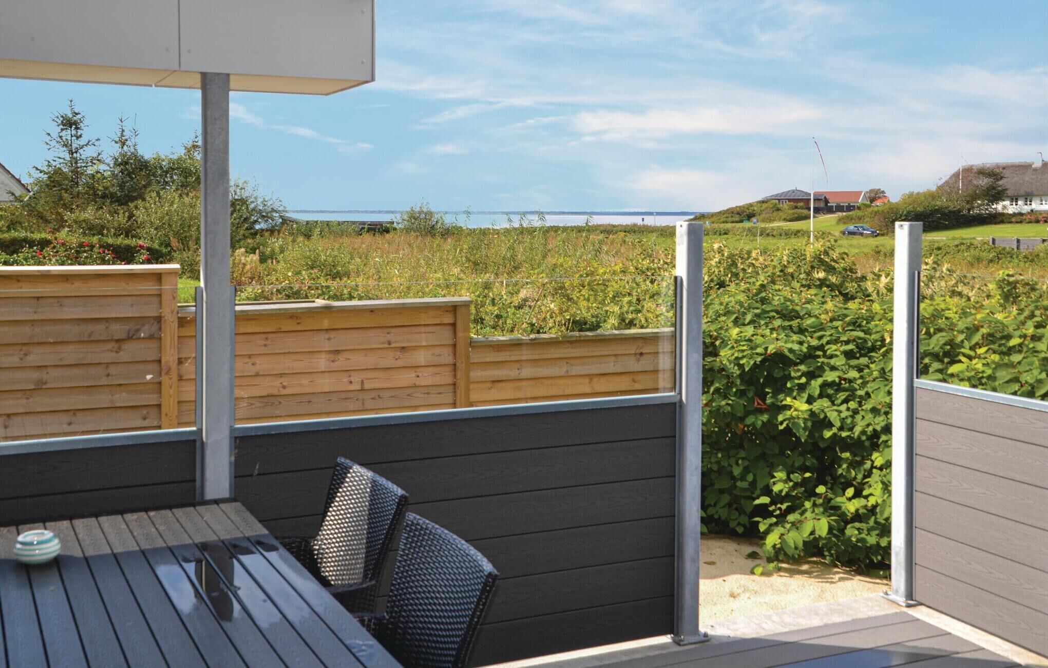 Una terraza con una mesa y sillas, con vista a un jardín y una vista distante de casas.
