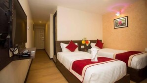 A hotel room with two beds, a TV, a desk, and a hallway leading to another room. - Hotel Tryst (Bhaktapur)