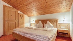 Une chambre à coucher en bois, avec un lit, des tables de chevet et un plafond en bois.