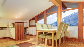 Une cuisine compacte avec un coin repas, un plancher en bois et de grandes fenêtres offrant une vue sur les montagnes.