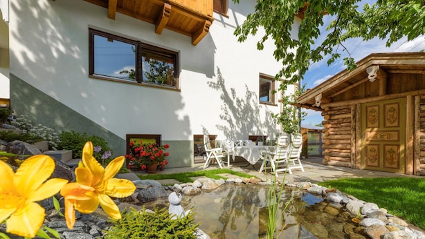 Une maison moderne avec un bassin en pierre, des murs blancs et un chalet en bois.
