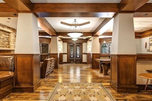 Un hall d’hôtel avec un plancher en bois, un tapis à motifs et un lustre.