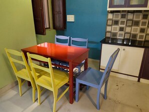 Compact kitchen with dining area, featuring a rectangular table and four chairs, a white cabinet, and a black countertop.