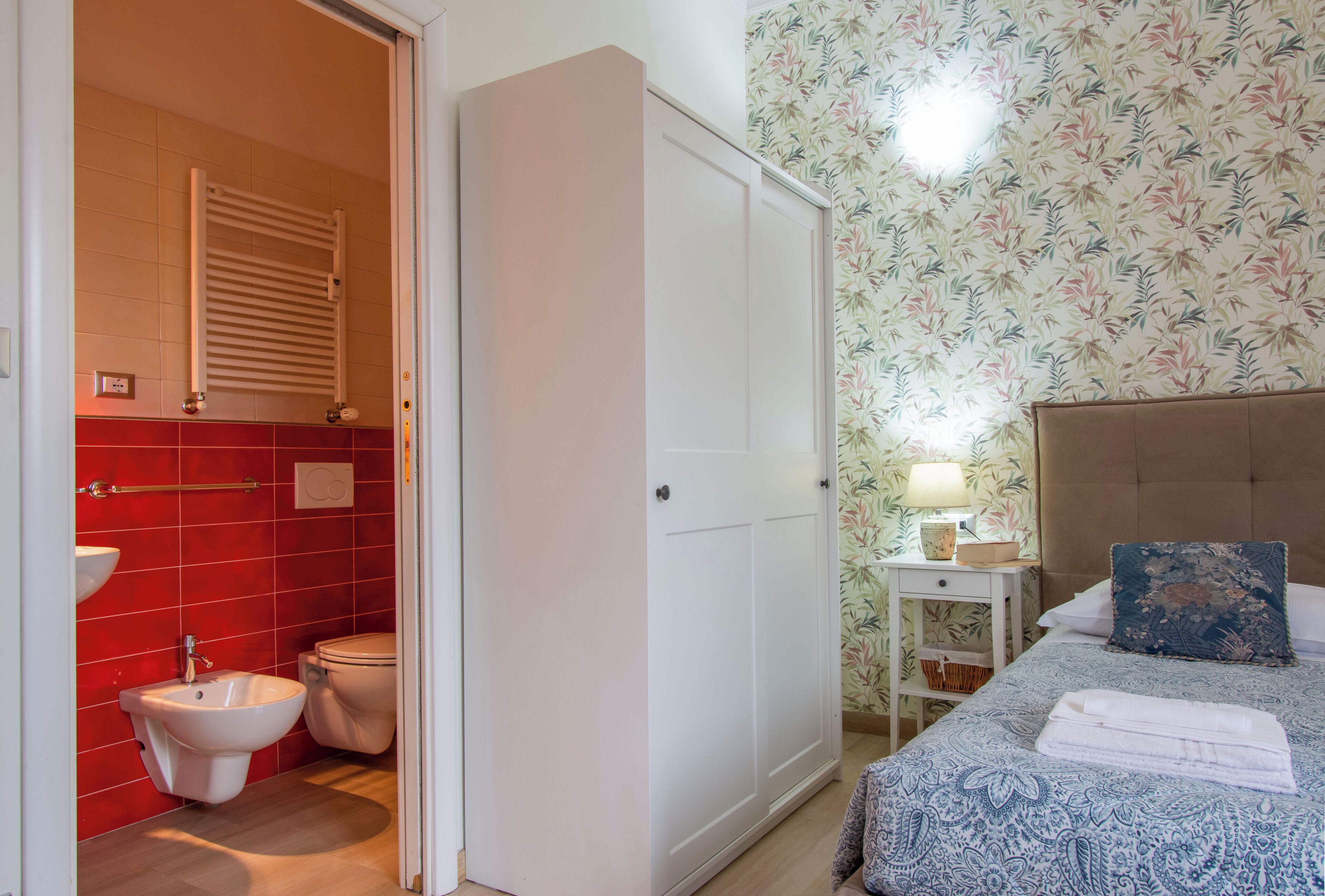 Une salle de bain équipée d’un bidet, de toilettes et d’un mur recouvert de carreaux rouges.
