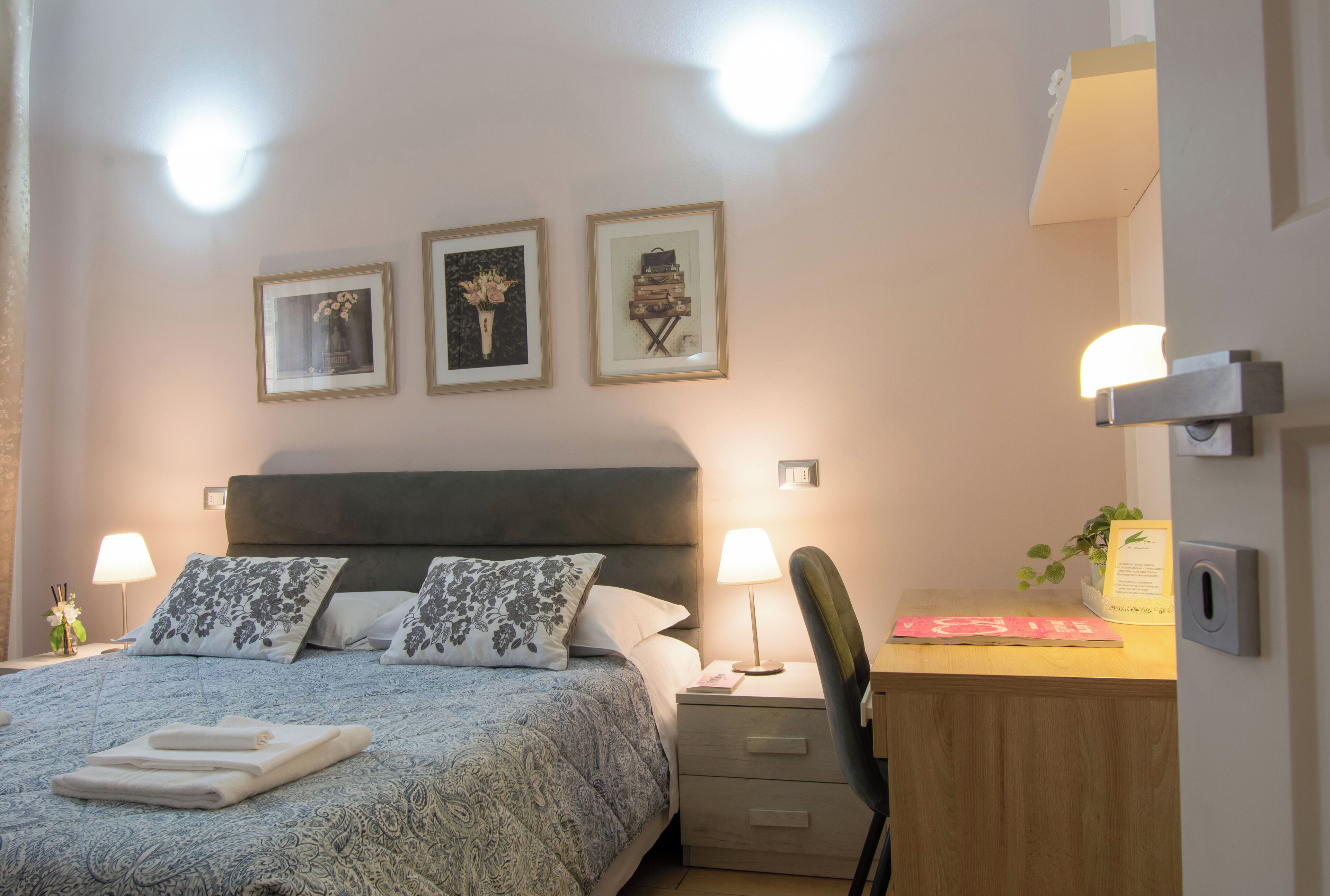 Ein Schlafzimmer mit einem Bett, Nachttischen, einem Schreibtisch und Wandleuchten.