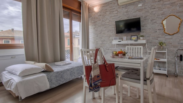 Una habitación con una cama, una mesa de comedor, sillas, un televisor y una pared de ladrillo.