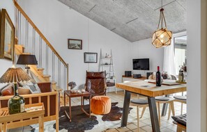 Relax in a cozy living space with a comfortable armchair, dining area, and mounted television.