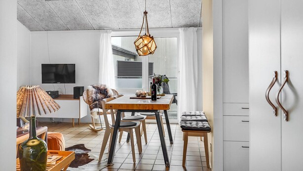 Uma cozinha moderna com área de jantar, com uma mesa de madeira, cadeiras e um lustre.