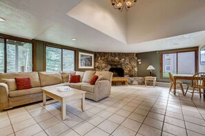 A spacious living room with a stone fireplace, a sofa set, a coffee table, and a dining area with a table and chairs.