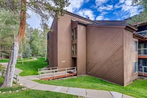 A modern building with a wooden exterior, a covered outdoor area, and a paved walkway.
