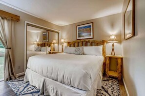 A large bed with a headboard, bedside lamps, and a mirror.