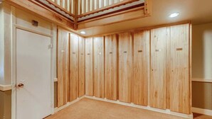 A room with wooden panel walls, a white door, and a ceiling with a wooden beam structure.