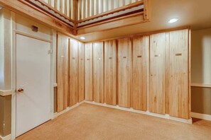 A room with wooden panel walls, a white door, and a ceiling with a wooden beam structure.