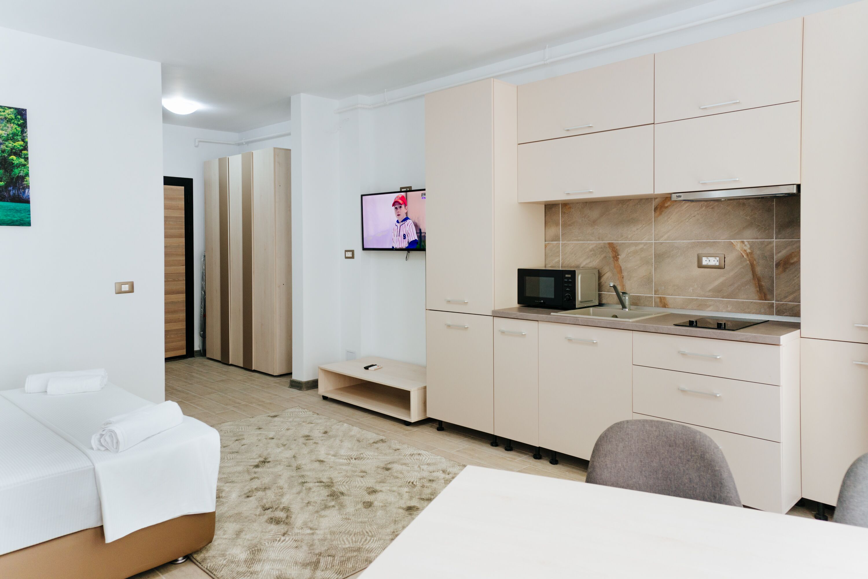 Una habitación de hotel moderna con cama, televisión, kitchenette y baño.