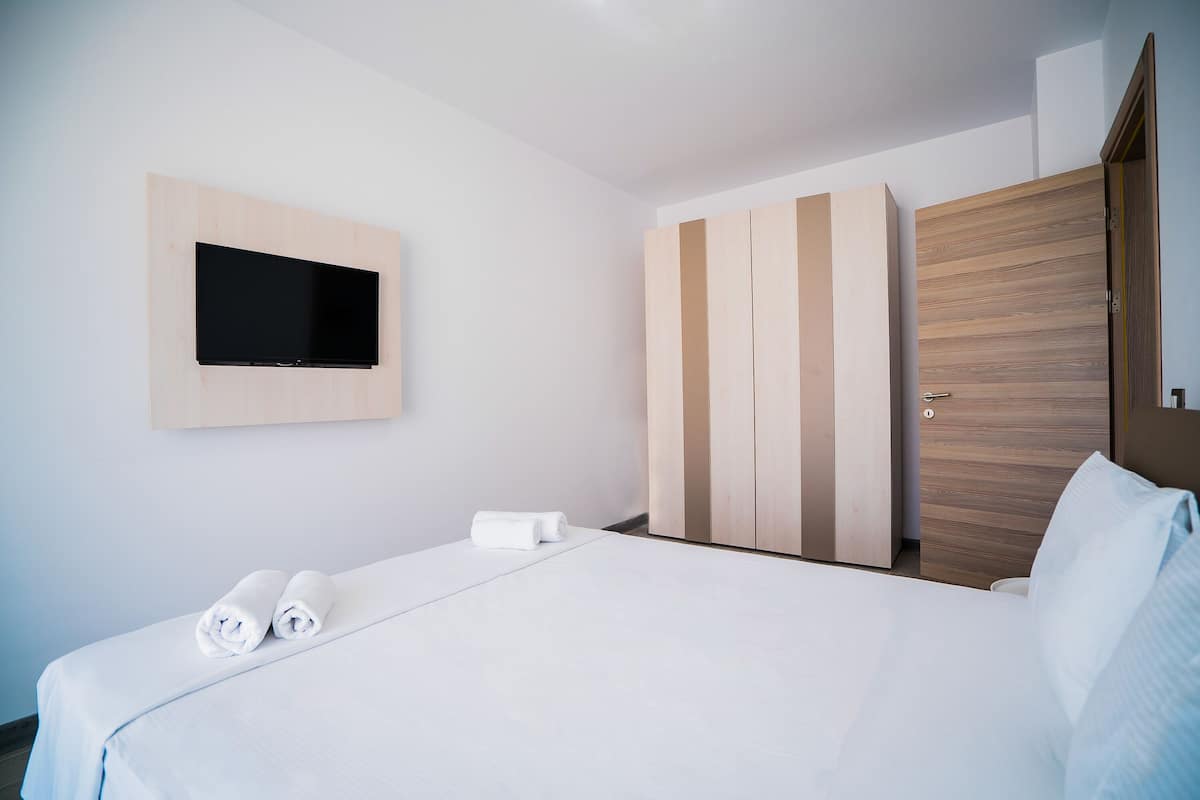 Una habitación de hotel con cama, televisor en la pared y armario.
