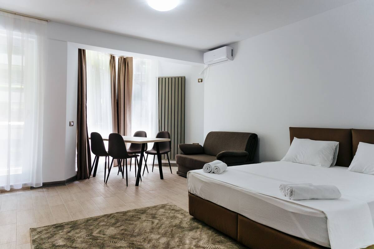 Una habitación de hotel con cama, escritorio, sillas y ventana con cortinas.
