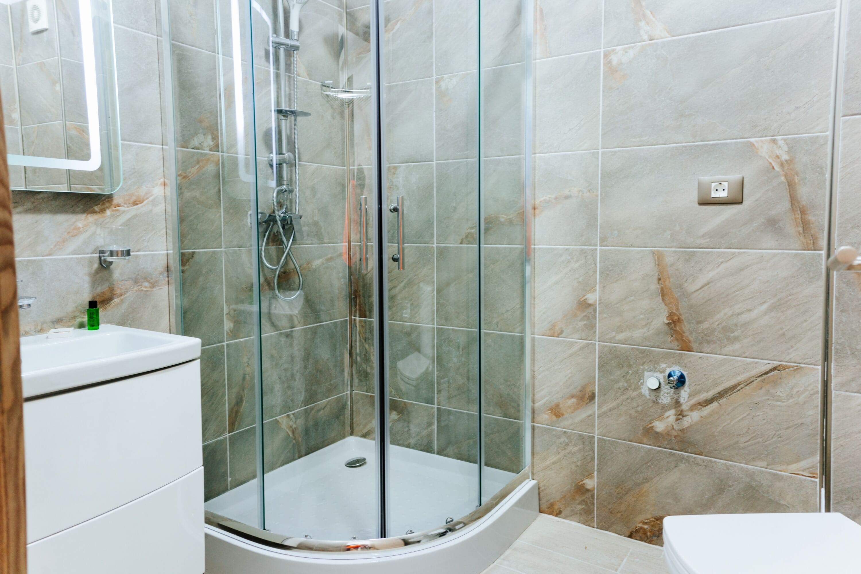 A modern bathroom with a glass-enclosed shower, a white sink, and a toilet.
