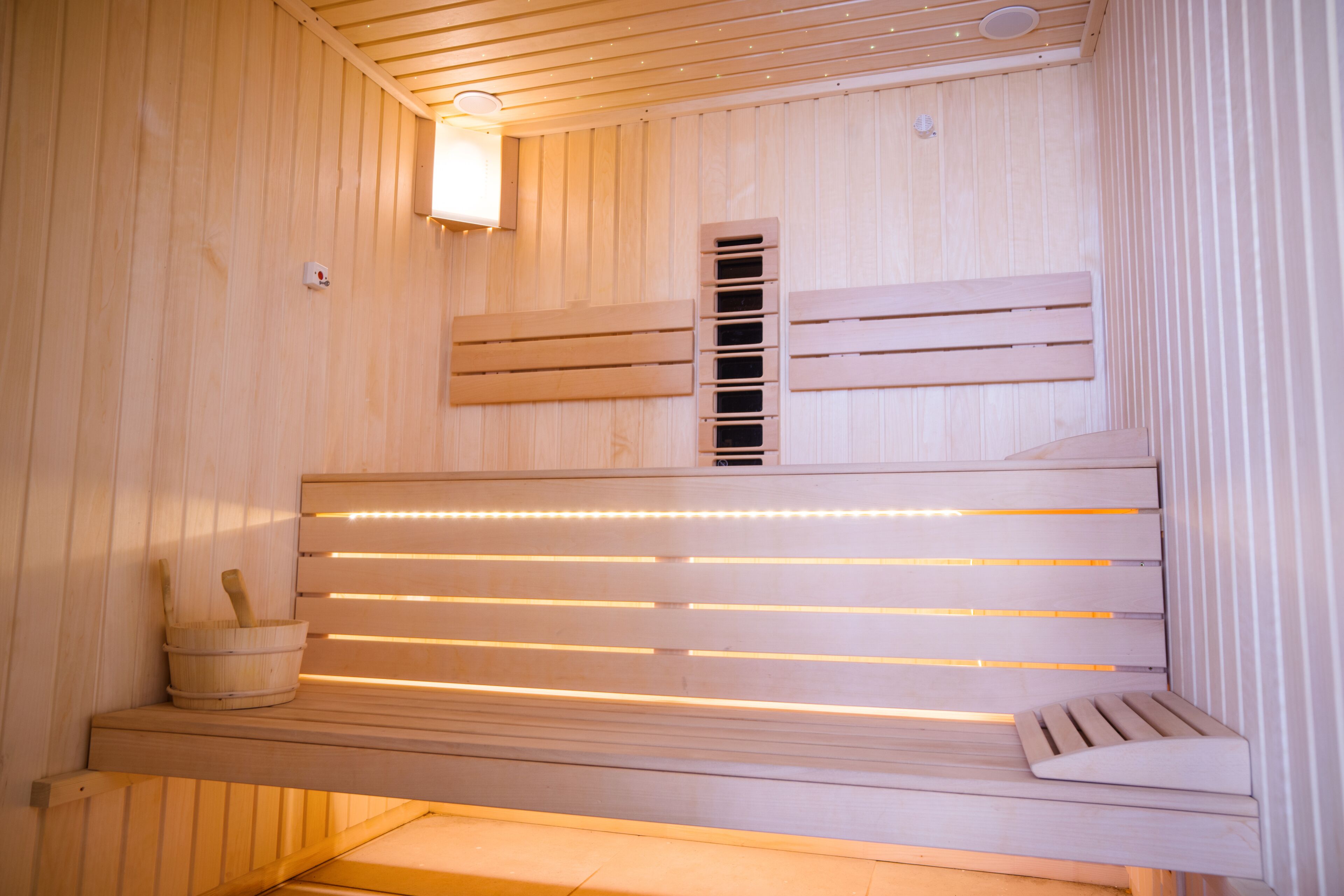 A wooden sauna with benches and a wall-mounted heater.