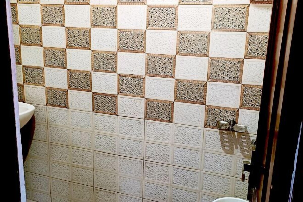 Un baño con pared revestida de azulejos que presentan un diseño geométrico en tonos beige y blanco.