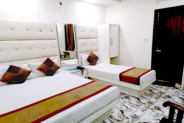 A hotel room with two beds, each with a red and white patterned bedspread, a white headboard, and a mirror above the beds. - Hotel Crystal Deluxe at New Delhi Railway Station (New Delhi)
