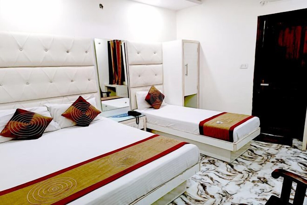 Habitación de hotel con dos camas, un armario, un espejo y una puerta.