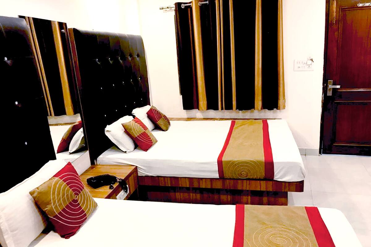 Een hotelkamer met twee bedden, een houten hoofdeinde en een rood-goud gestreept beddegoed.