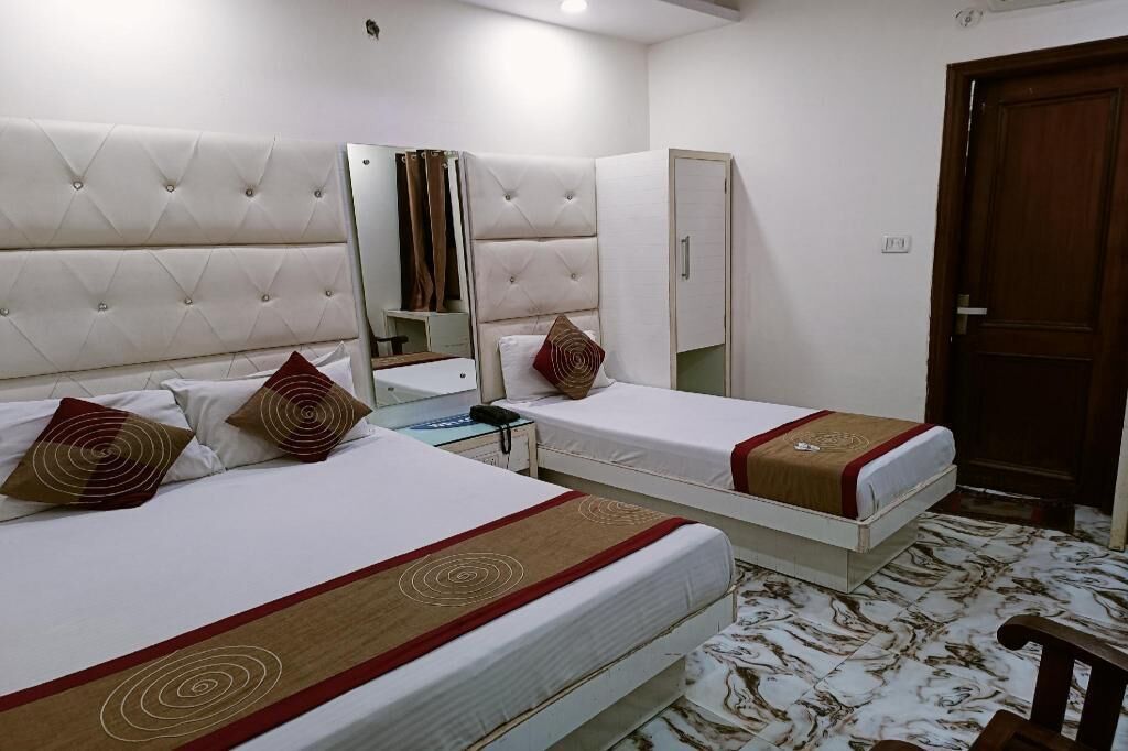 A hotel room with two beds, a mirror, a wardrobe, and a wooden door.