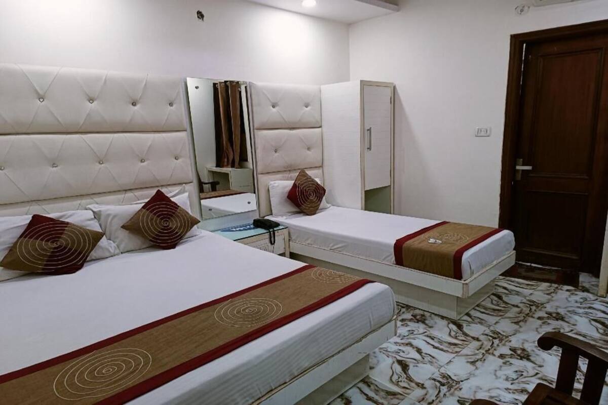 Een hotelkamer met twee bedden, een spiegel, een kledingkast en een houten deur.