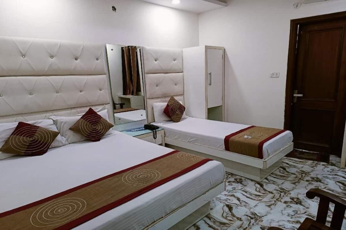 A hotel room with two beds, a mirror, a wardrobe, and a wooden door.