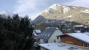 Ein Berg mit schneebedeckten Gipfeln, eine Kirche und Wohnhäuser mit geneigten Dächern.