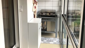 Eine kompakte Küche mit Gasherd, weißen Schränken und einer gefliesten Spritzschutzwand.