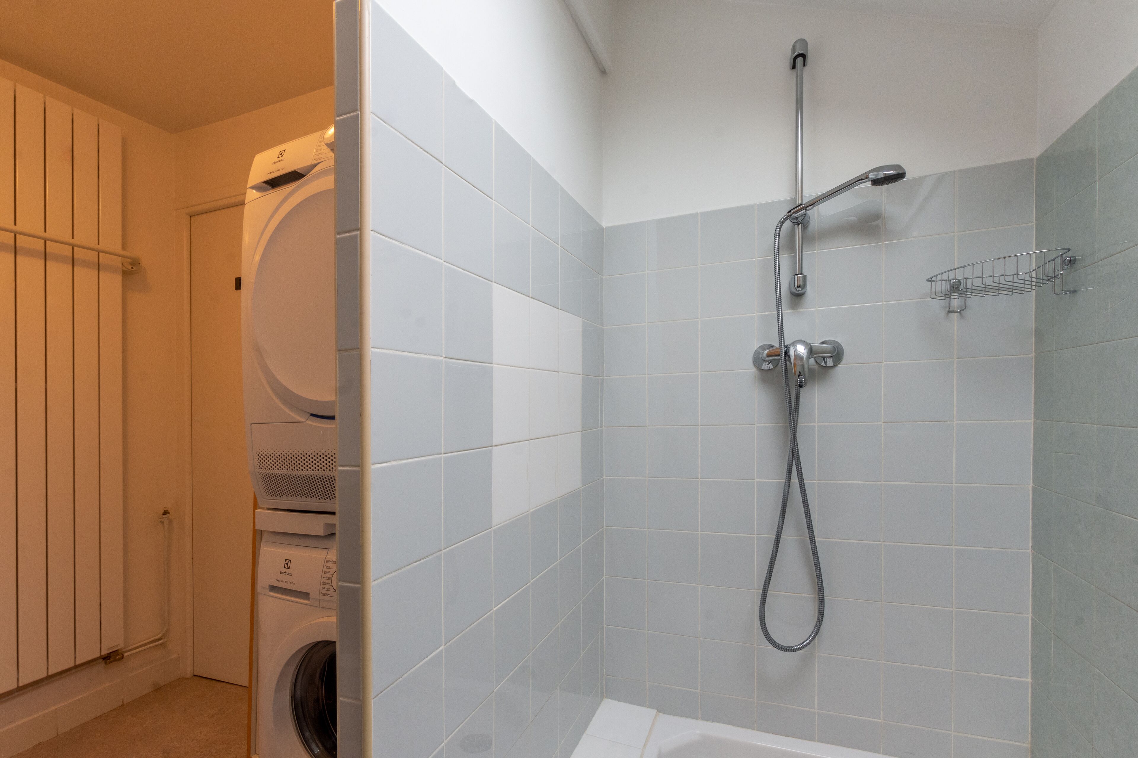 A bathroom with a shower, a toilet, and a washing machine.