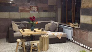 Un salón acogedor con un sofá, una mesa de madera y un jarrón con flores.