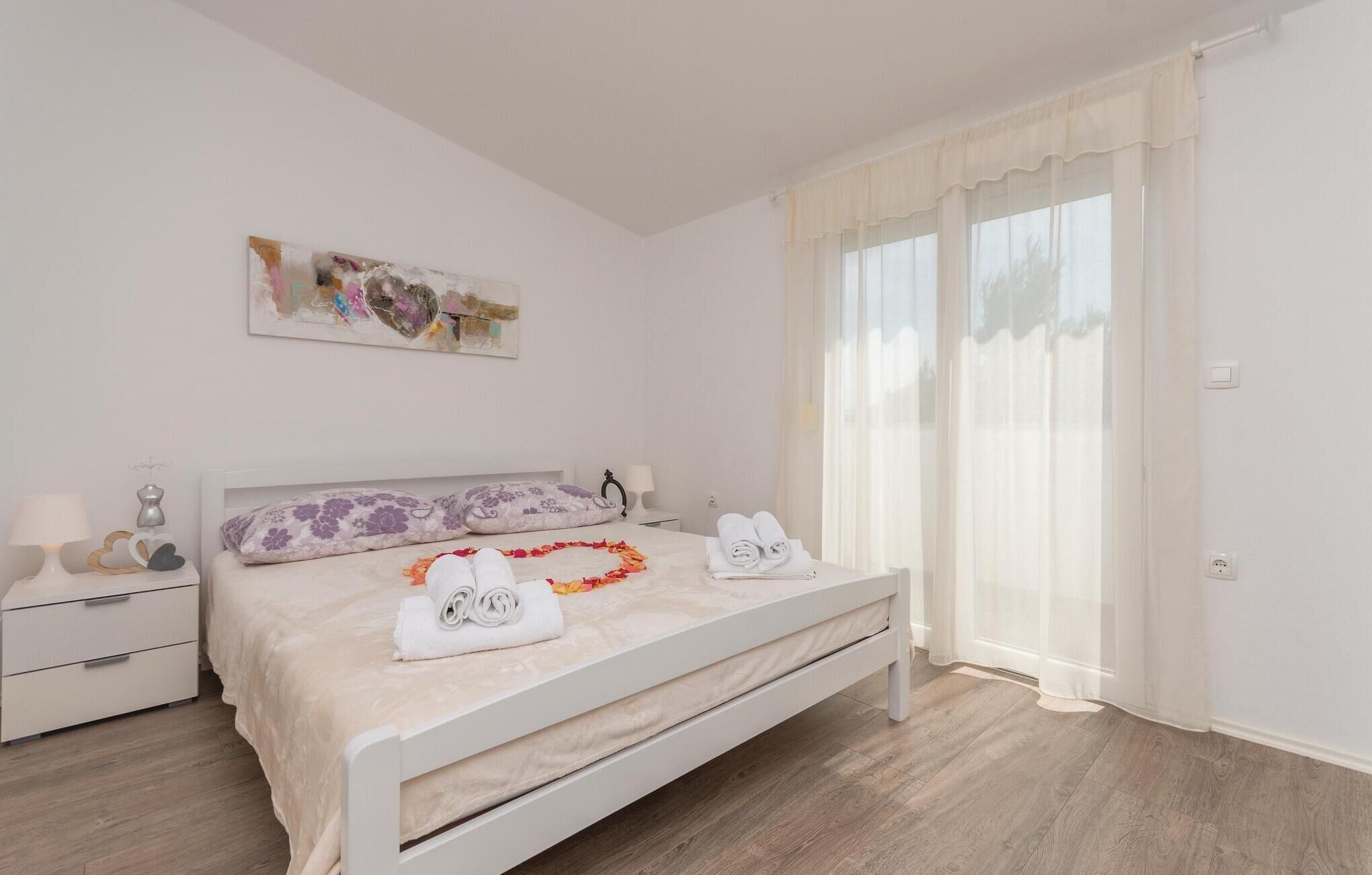 A bedroom with a bed, a nightstand, a lamp, and a window with curtains.