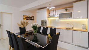 Een moderne keuken met witte kasten, een inbouwoven, een magnetron en een koffiezetapparaat.