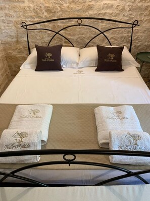A neatly made bed with two pillows and two towels on a metal bed frame.