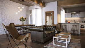 Ein modernes Wohnzimmer mit Ledersofa, einem Esstisch mit Stühlen und einer Küchenzeile mit Barhocker.