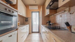 Een moderne keuken met een inbouwoven, een koffiezetapparaat en een messenblok.