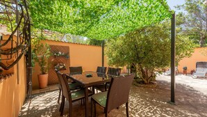 Een terras met een tafel en stoelen, omringd door planten en een hek.