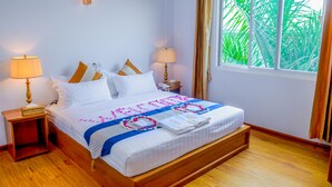 A neatly made bed with a floral bedspread, two bedside lamps, and a window with curtains. - City Light Hotel (Nyaungshwe)