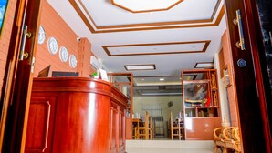 A reception area with a wooden counter, clocks on the wall, and a ceiling with geometric patterns. - City Light Hotel (Nyaungshwe)