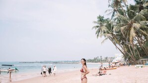 A beach with palm trees, a sandy shore, and a calm sea. - Hasaranga Holiday House (Hikkaduwa)