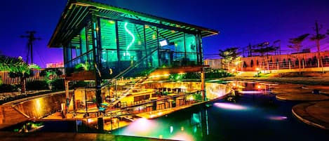 A modern building with a glass facade and a pool area.