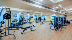 Un gimnasio con equipo de ejercicio diverso, suelo de madera y pared espejada.