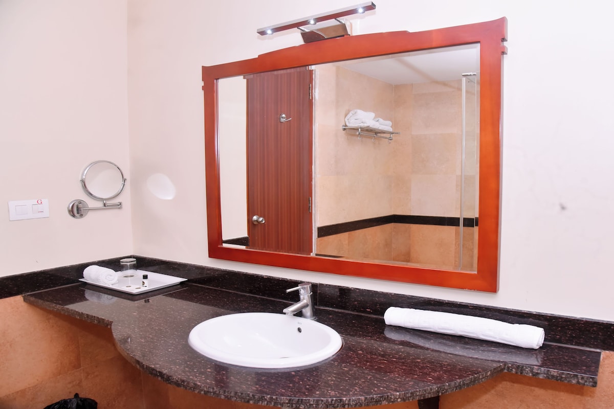A bathroom with a marble sink, a mirror, a towel rack, and a shower area.