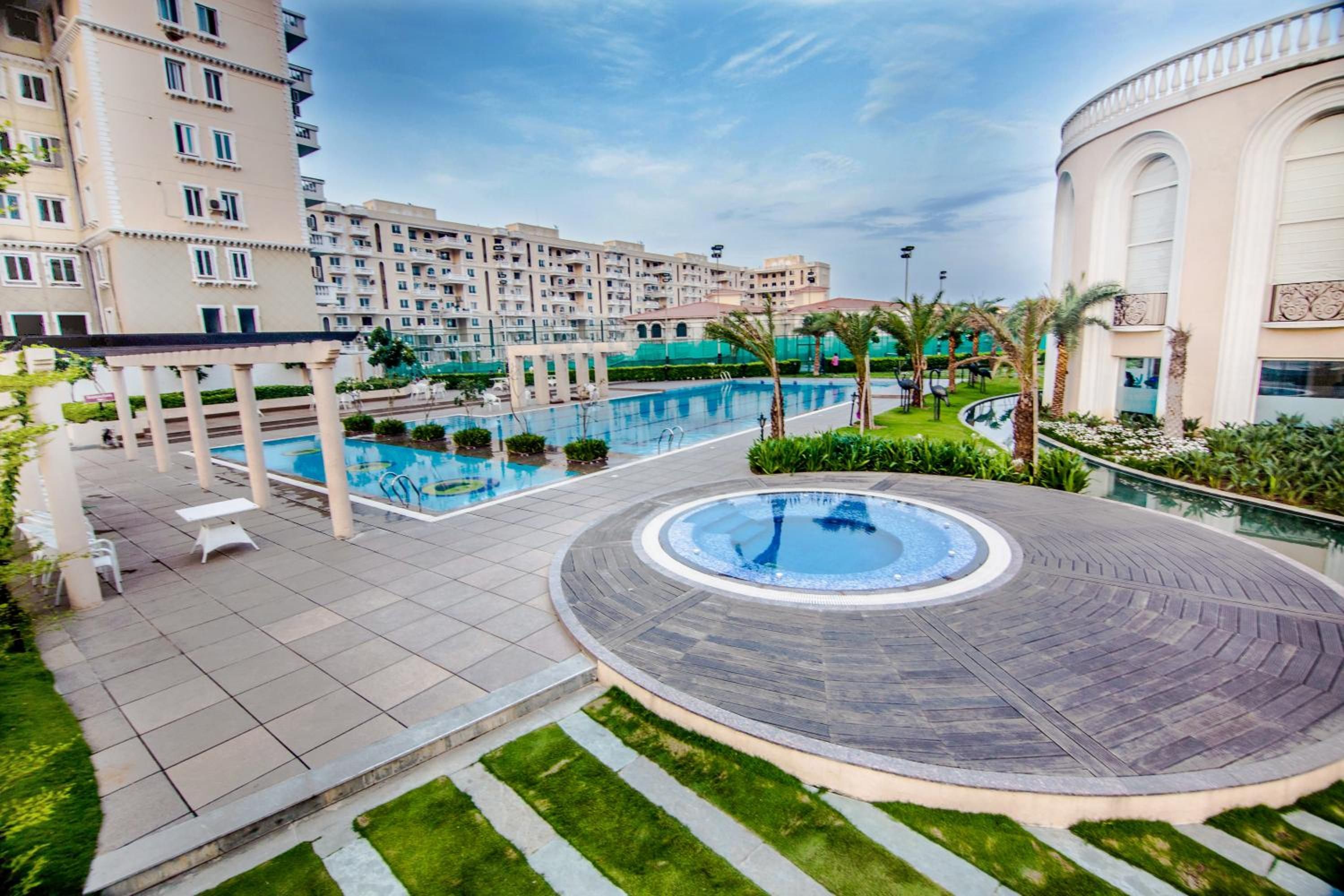 A residential complex with a swimming pool, a hot tub, and a landscaped garden area.