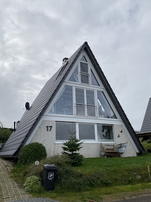 A triangular-shaped building with large windows and a satellite dish.