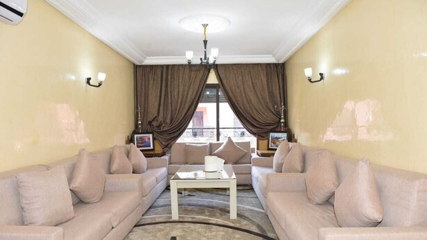 Un salon avec deux canapés beige, une table basse blanche et des rideaux marron.