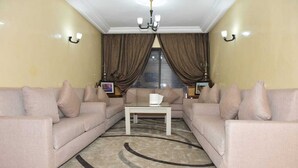 Un salon avec des canapés de couleur beige, une table basse blanche et un tapis à motifs.