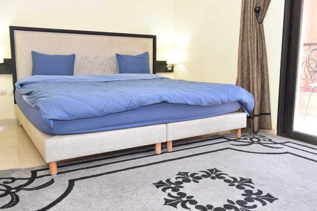 Un lit avec une tête de lit, une table de chevet avec une lampe et un tapis à motifs.